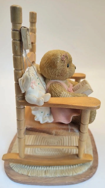 Teddy bear in a high chair with baby clothes and toys on a white background