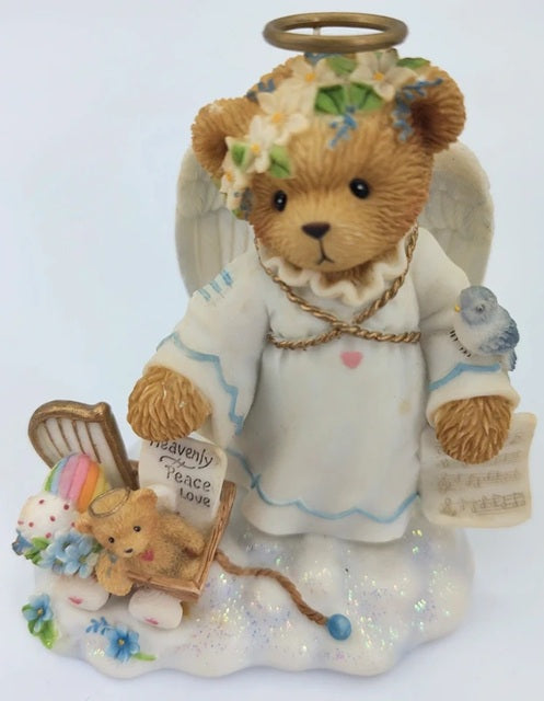 Decorative angel figurine with a teddy bear holding a book on a white background