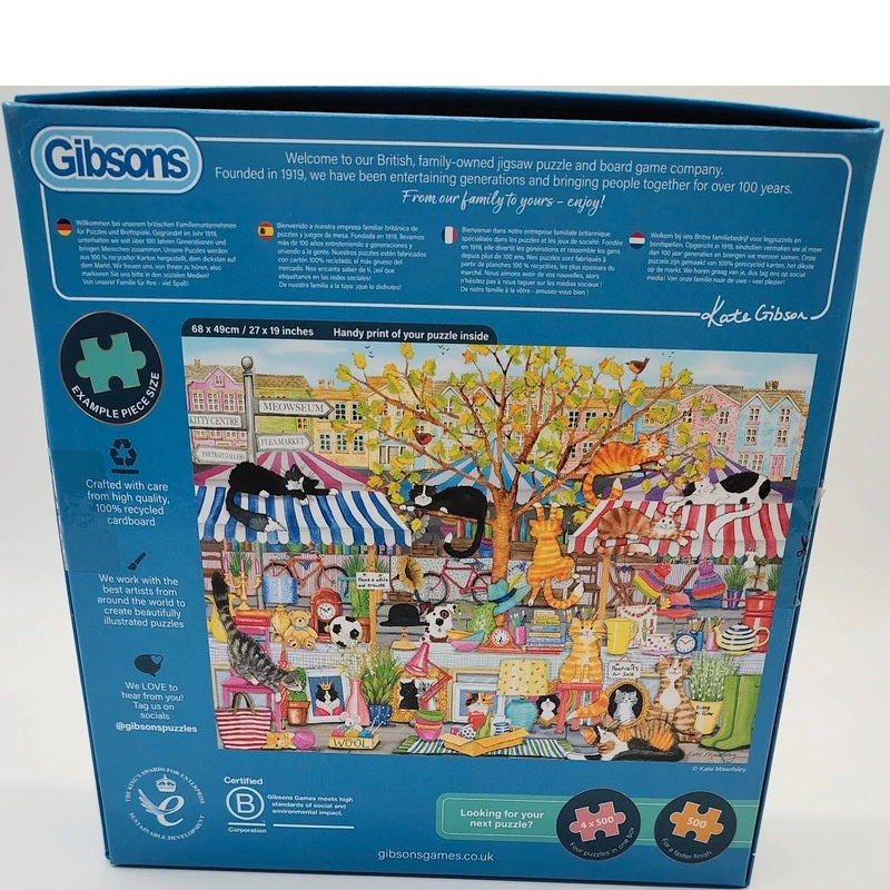 Gibson 1000-piece jigsaw puzzle box featuring a colorful illustrated market scene with cats, trees, and storefronts on the front, photographed against a plain light background.