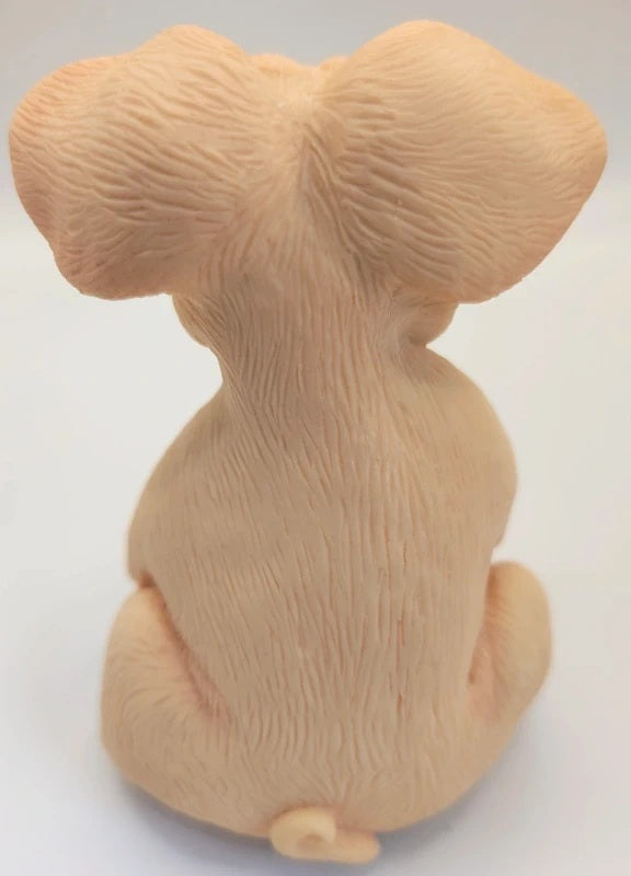 A beige figurine of a pig seen from the back, featuring detailed fur texture and ears, set against a plain white background.