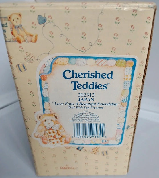 A boxed collectible item labeled 'Cherished Teddy' with teddy bear illustrations and a blue-bordered label on a cream floral package.