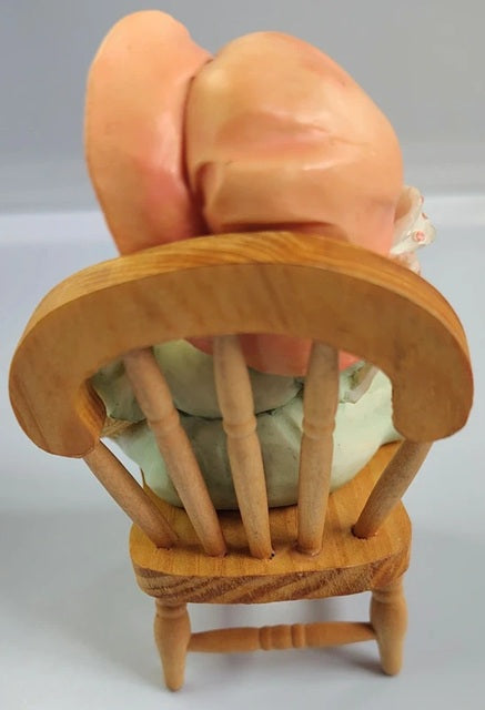 Wooden chair with a Cherished Teddy bear on top against a gray background