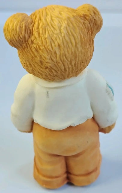 Back view of a teddy bear with a white shirt and orange pants on a white background