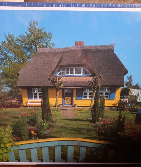 Yellow house with a thatched roof in a garden setting