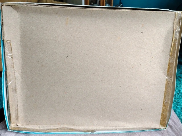 Rectangular cardboard box with a gold rim on a blue surface