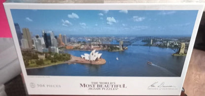 Puzzle box featuring a scenic view of a city with a bridge and a famous landmark.