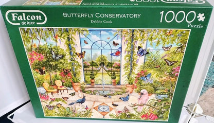 Jigsaw puzzle box featuring a butterfly conservatory scene with 'Falcon de luxe' branding.