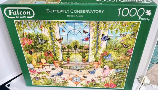 Jigsaw puzzle box featuring a butterfly conservatory scene with 'Falcon de luxe' branding.