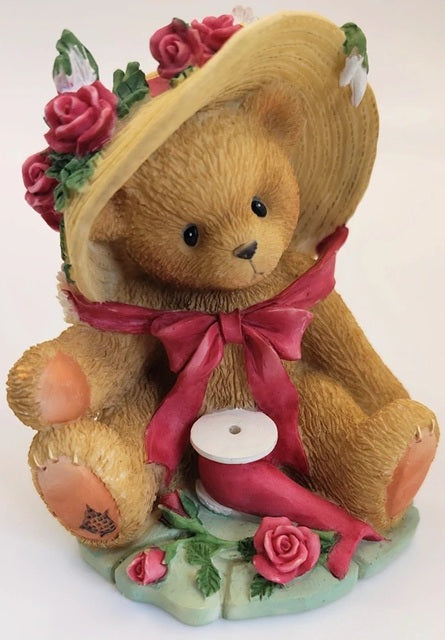 Cherished Teddies Janet teddy bear figurine with a pink bow and floral decorations on a white background
