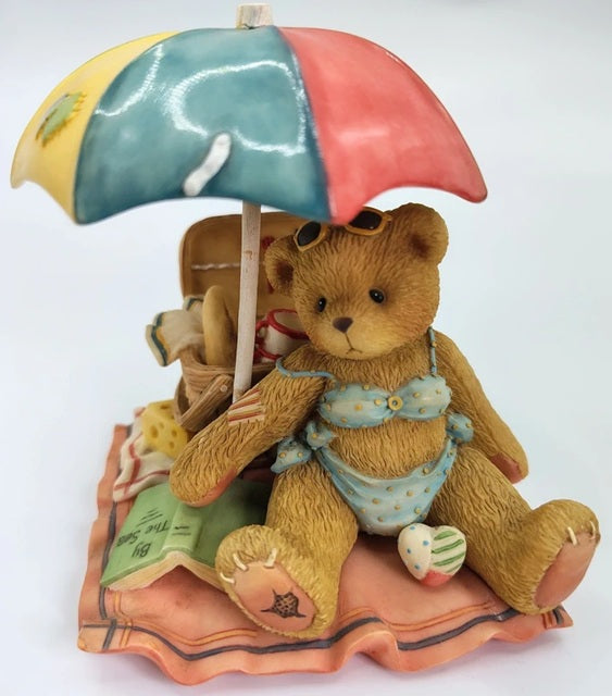 Cherished Teddies Judy 'I'm Your Bathing Beauty' figurine. Teddy bear with a colorful umbrella and beach accessories on a white background