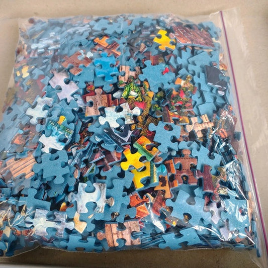 Pile of assorted puzzle pieces in a clear bag on a cardboard surface