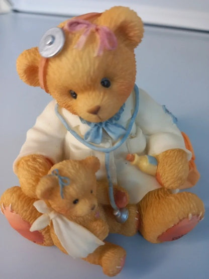 Teddy bear dressed as a doctor holding a smaller teddy bear on a light blue background