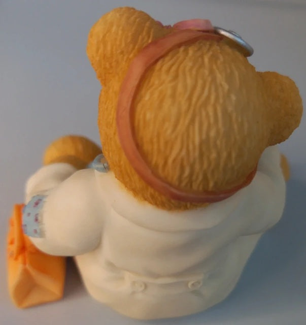 Toy bear with a pink headband on a plain background