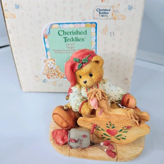 Cherished Teddies figurine with a teddy bear on a wooden platform, in front of a Cherished Teddies box.