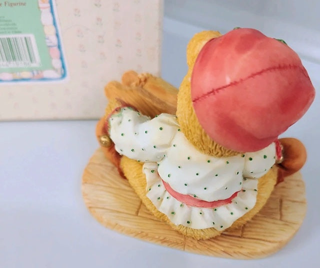 Toy figure of a cactus with a peach on top, placed on a wooden surface.