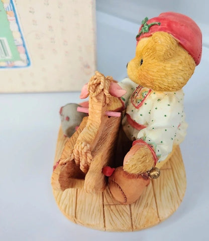 Decorative figurine of a bear with a child and a dog on a sled, with a red hat and white coat.