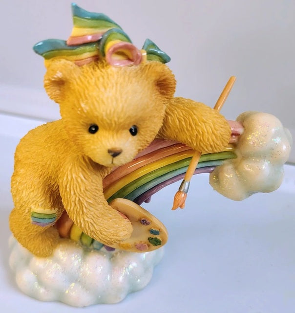 Teddy bear figurine with rainbow and paintbrush on a white background