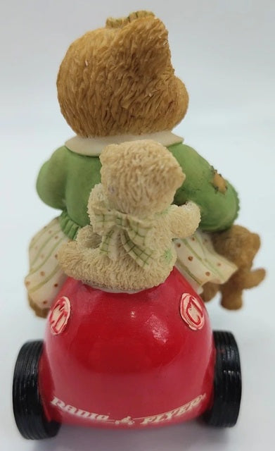 Toy figure of a child on a red scooter with a teddy bear, on a white background