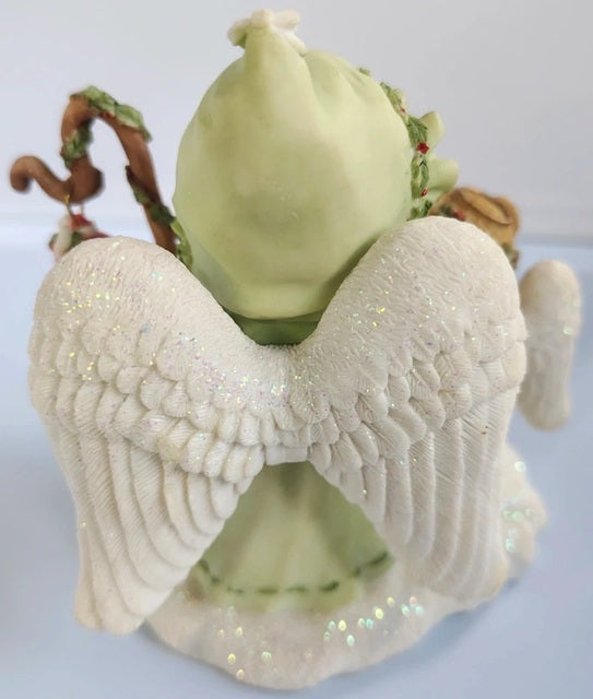 Decorative angel figurine with a green bag on a white background