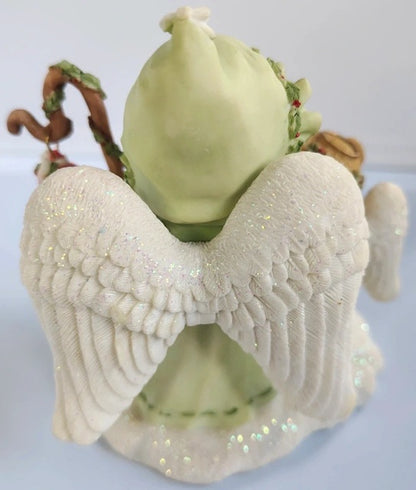 Decorative angel figurine with a green bag on a white background