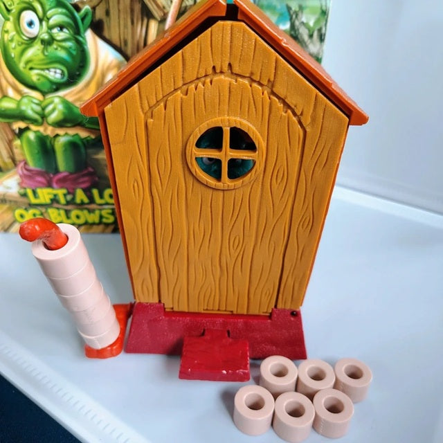 Toy birdhouse with a red base and wooden texture, accompanied by small circular objects on a white surface.