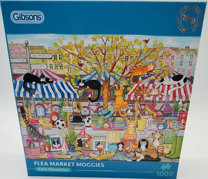 A 1000-piece jigsaw puzzle box by Gibson titled 'Flea Market Moggies' by Kate Mawdsley. The box art features a highly detailed, colorful illustration of various cats gathered at a bustling outdoor flea market under striped awnings, with a large tree in the center.