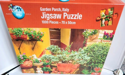 A jigsaw puzzle box for 'Garden Porch, Italy' by Puzzle World, featuring a 1000-piece puzzle (70 x 50 cm) with an illustration of a Mediterranean garden porch scene.