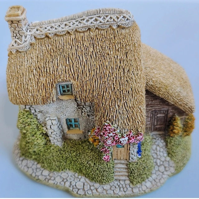 Model of a thatched cottage with decorative elements on a white background