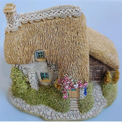Model of a thatched cottage with decorative elements on a white background