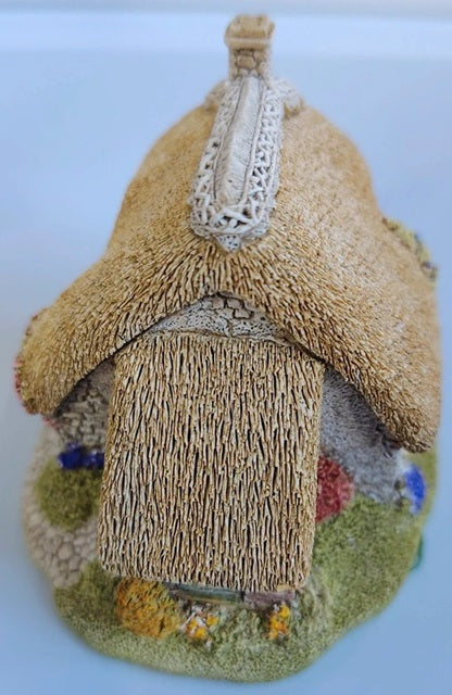 Textile art of a small house with a thatched roof on a white background