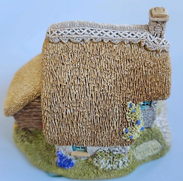 Miniature model of a thatched cottage with decorative elements on a white background