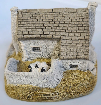 Model of a stone building with sheep in a pen on a white background