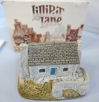 Small model of a stone cottage with a box labeled 'Lilliput Lane' in the background.