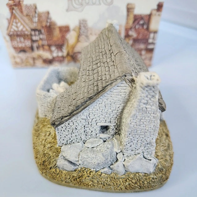 Miniature model of a stone cottage with a thatched roof on a white background