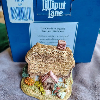 Miniature thatched cottage figurine in front of a Lilliput Lane box