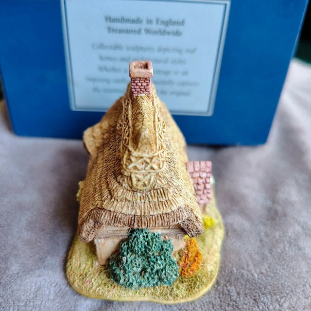 Small model of a thatched-roof house with a blue box in the background