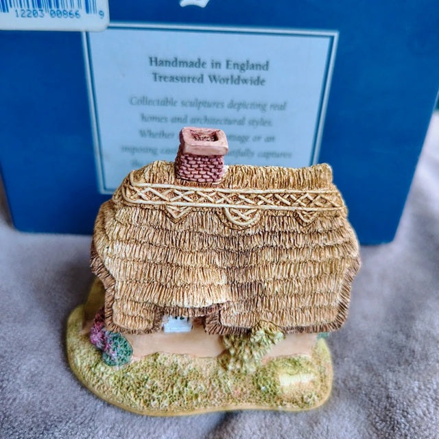 Miniature thatched cottage figurine with a blue box in the background