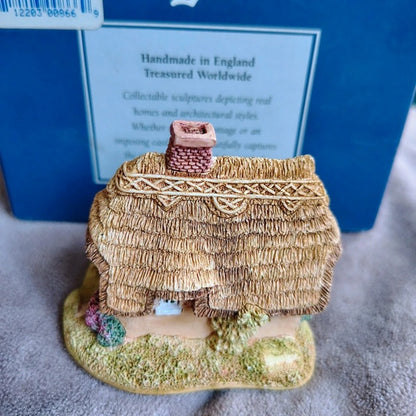 Miniature thatched cottage figurine with a blue box in the background