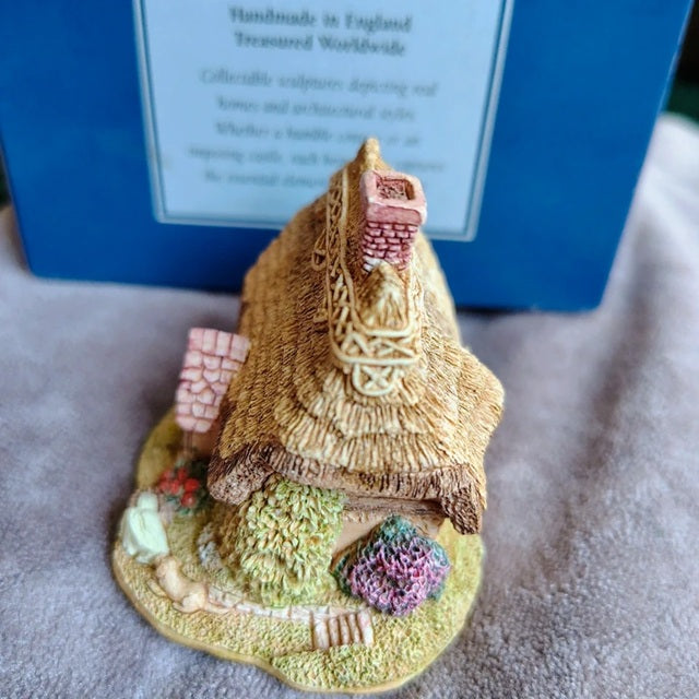 Small decorative house figurine with thatched roof on a textured surface