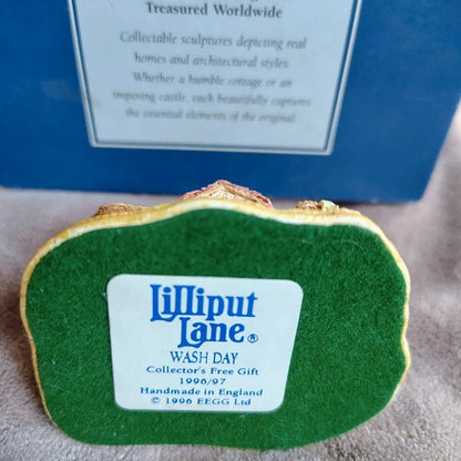 Green Lilliput Lane collectible with a label in front of a blue box