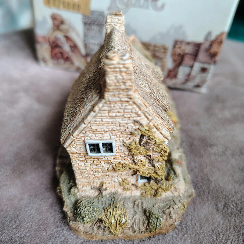 Small model of a thatched cottage on a textured surface with blurred background
