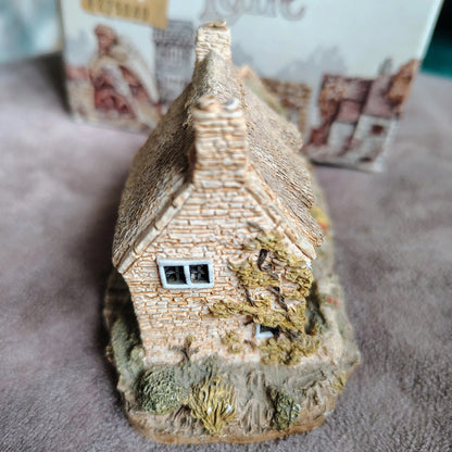 Small model of a thatched cottage on a textured surface with blurred background