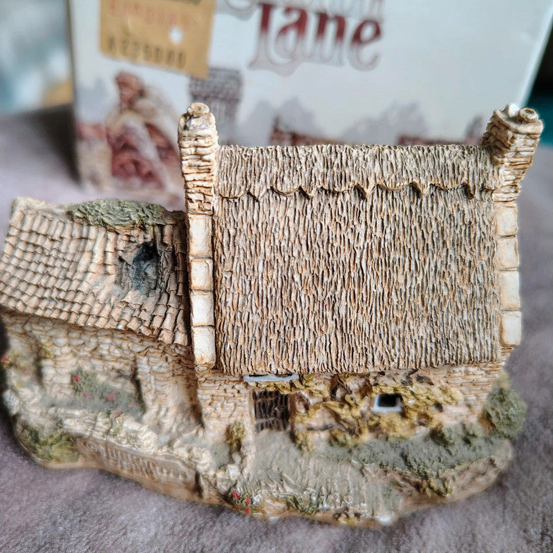 Small model of a thatched cottage on a textured surface with a blurred background