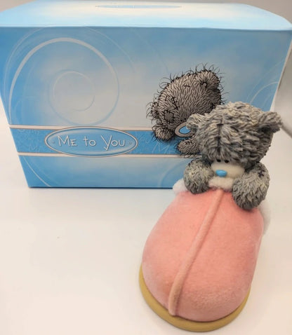 A Me to You Cosy Feet resin bear figurine with gray fur and blue eyes, sitting on a pink cushioned base, with its blue branded box behind it on a white background.