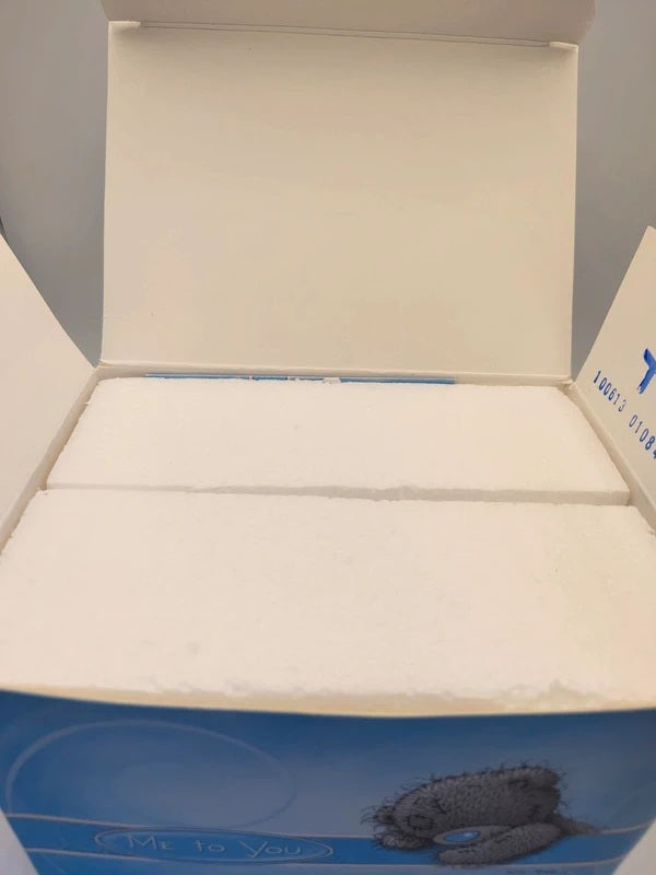 An open white product box with a blue printed base, showing white foam inserts inside. The box features a teddy bear illustration and the text 'Mr.