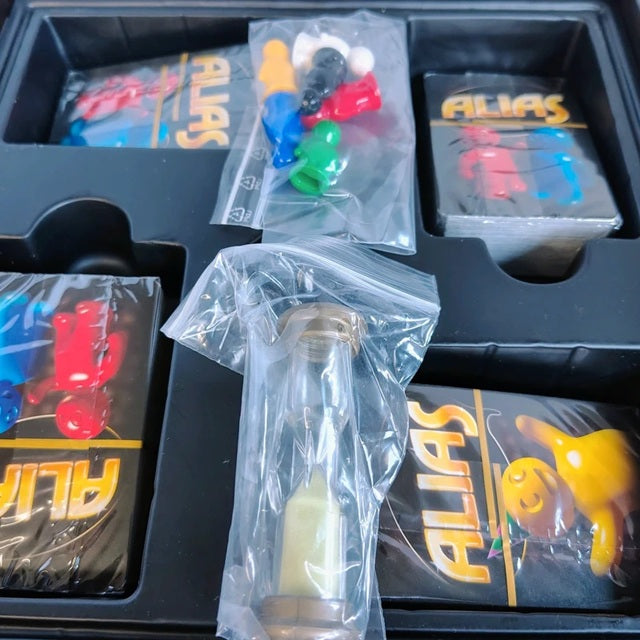 Board game components including cards and plastic bags with game pieces on a black tray.