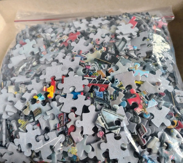 Pile of puzzle pieces in a clear plastic bag on a cardboard surface