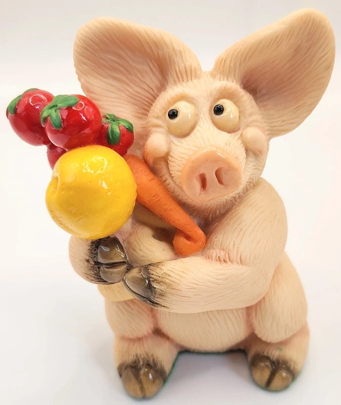 Piggin Diet figurine handmade by David Corbridge in 1997. A small pig figurine holding a carrot, a yellow ball, and red tomatoes, photographed against a plain white background.
