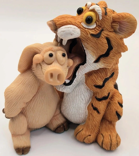 A stylized figurine of a tiger and a pig interacting closely, shown against a plain light background. Piggin Easy Tiger figurine.