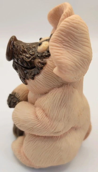 A small sculpted pig figurine with a textured, ribbed surface resembling fur or hide, featuring a dark brown snout, hooves, and a small cream-colored eye detail, set against a plain white background.